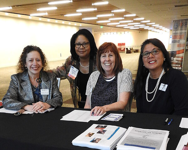 Group of smiling business women present at booth