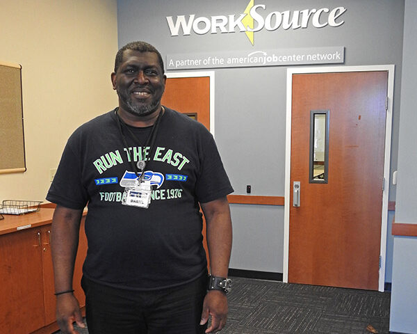 happy Man wears Run the East t shirt in front of Worksource entrance sign