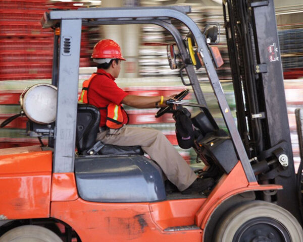 man working in warehouse with load lifter