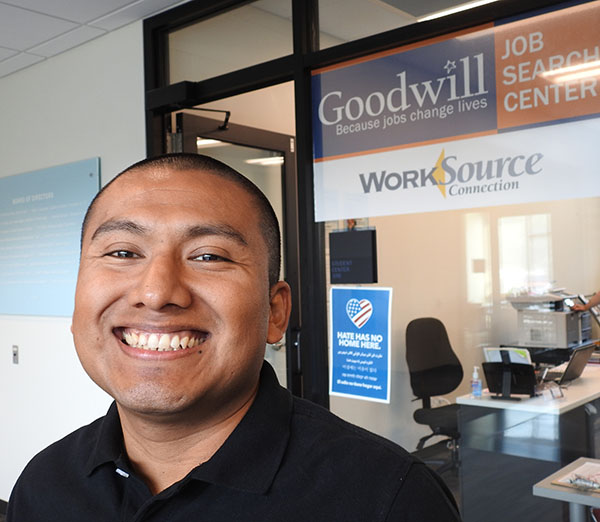 Worker smiles in front of Goodwill and WorkSource sign.